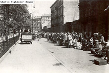 Deportowani Żydzi z fabryk Toebbensa w drodze na Umschlagplatz. Na zdjęciu po lewej widoczny niemiecki pojazd wojskowy z żołnierzami. 1943 r. Fot. nieznany. The Ghetto Fighters&apos; House Museum. Israel/ The photo Archive